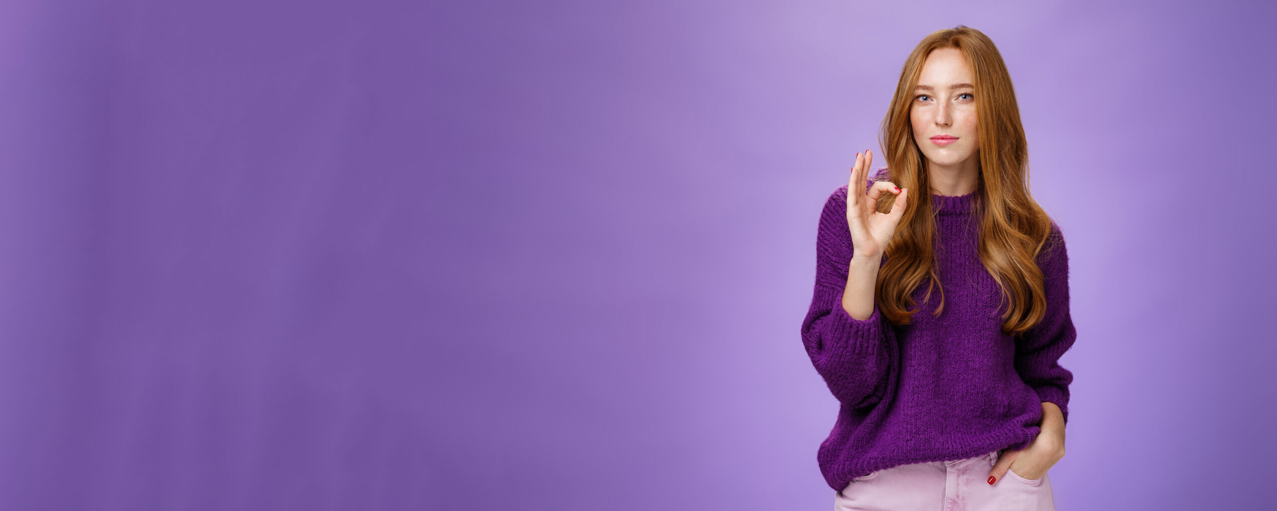 Nice work, cool. Portrait of delighted stylish and confident good-looking redhead female in purple sweater showing ok gesture as reacting to excellent job, proud of friend over violet wall